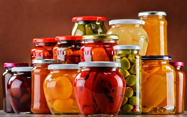 Jars with fruity compotes jams and pickled vegetables — Stock Photo, Image