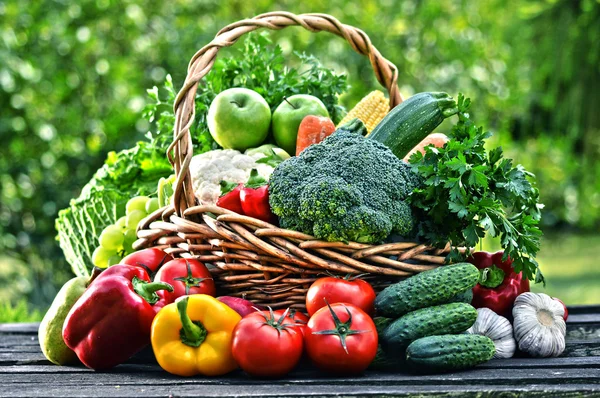 Cesta de mimbre con una variedad de verduras orgánicas crudas en el jardín — Foto de Stock