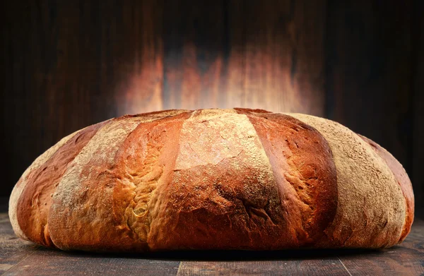 Loaf of large bread on wooden table — Stock Photo, Image