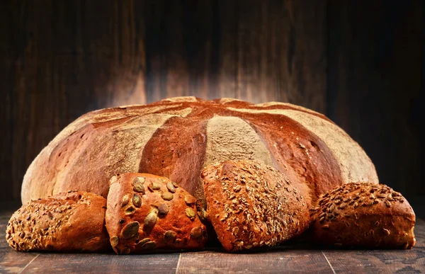 Composition with large loaf of bread and four rolls — Stock Photo, Image