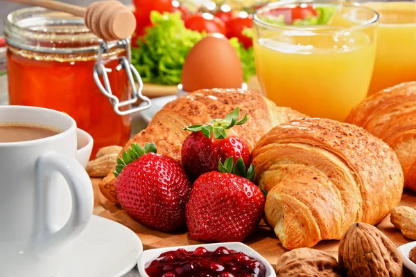 Breakfast consisting of croissants, coffee, fruits, orange juice