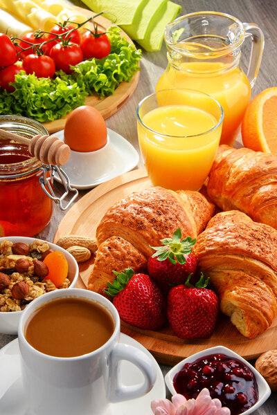 Breakfast consisting of croissants, coffee, fruits, orange juice