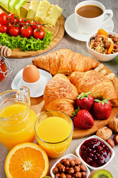 Breakfast consisting of croissants, coffee, fruits, orange juice