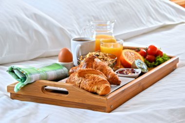 Otel odasında yatakta kahvaltı tepsisi