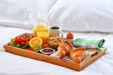 Otel odasında yatakta kahvaltı tepsisi