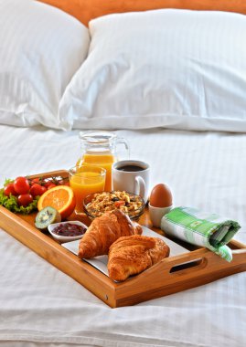 Otel odasında yatakta kahvaltı tepsisi