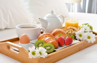 Otel odasında yatakta kahvaltı tepsisi