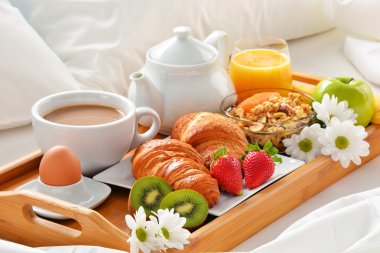 Otel odasında yatakta kahvaltı tepsisi