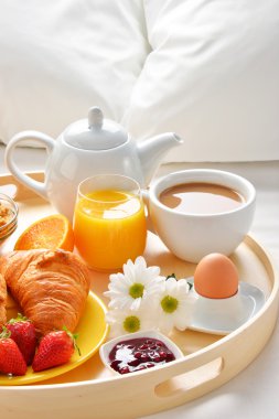 Otel odasında yatakta kahvaltı tepsisi