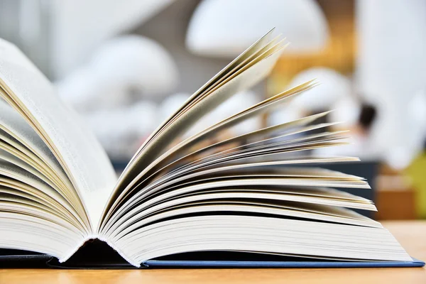 Libro de tapa dura acostado sobre la mesa en una biblioteca —  Fotos de Stock