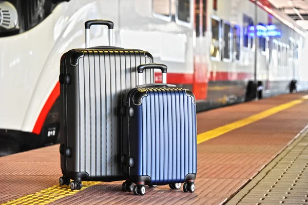 Two plastic travel suitcases on the railroad platform