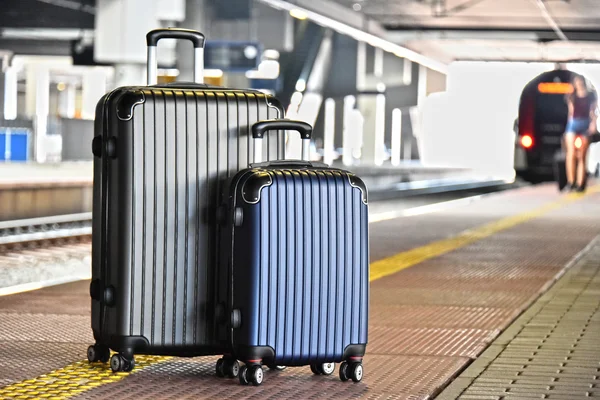 Two plastic travel suitcases on the railroad platform