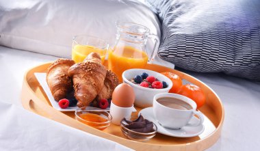 Otel odasındaki bir yatakta kahvaltı tepsisi..