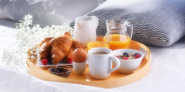 A tray with breakfast on a bed in a hotel room.