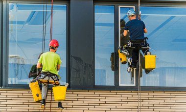 Ofis binasının camlarını temizleyen iki adam.