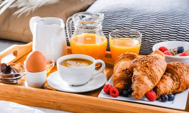 Otel odasındaki bir yatakta kahvaltı tepsisi..