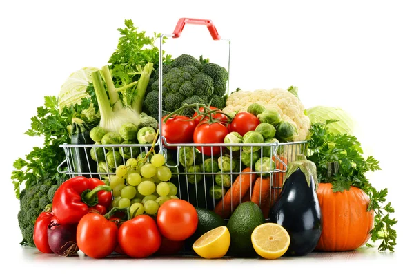 Cesta de compras com legumes orgânicos crus variados sobre branco — Fotografia de Stock