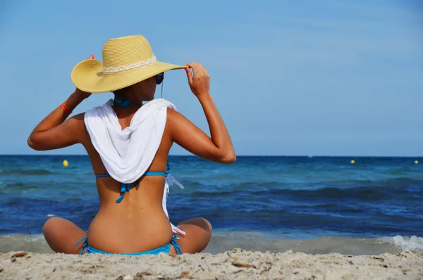 Fiatal nő ül a mediterrán tengerparton a forró nyári napon — Stock Fotó
