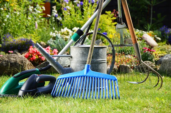 Gieter en gereedschap in de tuin — Stockfoto