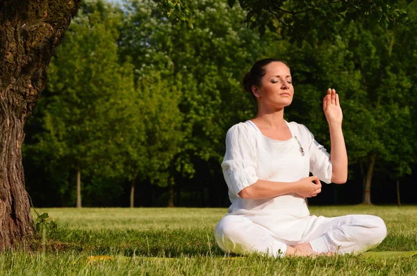 Jovem mulher durante meditação de ioga no parque — Fotografia de Stock