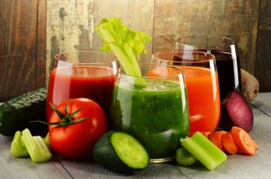 Glasses with fresh organic vegetable juices on wooden table clipart