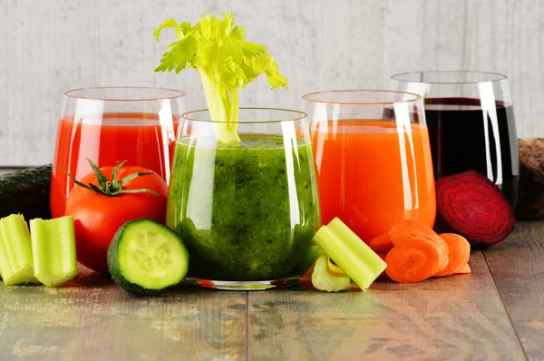 Glas med färska ekologiska vegetabiliska juicer på träbord — Stockfoto