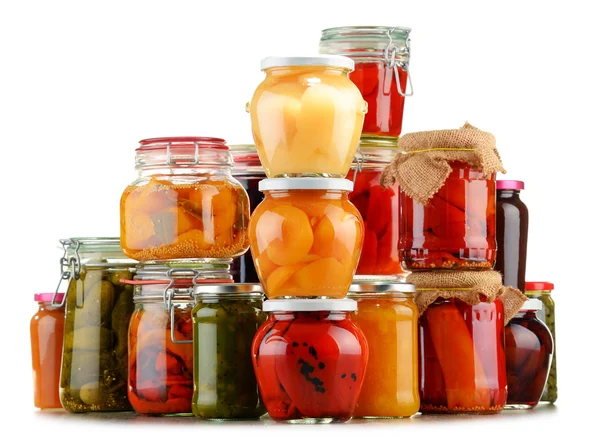 Gläser mit eingelegtem Gemüse und fruchtigen Kompotten auf weißem — Stockfoto