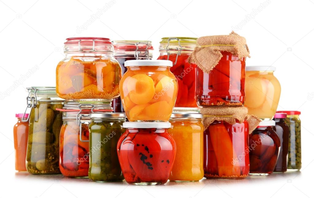 Jars with pickled vegetables and fruity compotes on white