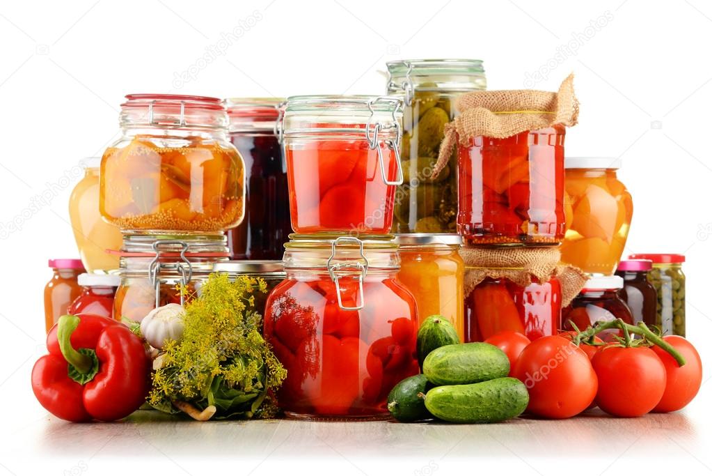 Jars with pickled vegetables and fruity compotes on white