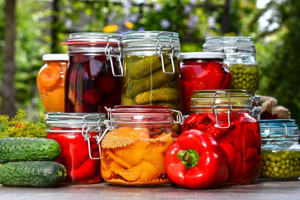 Gläser mit eingelegtem Gemüse und Obst im Garten — Stockfoto