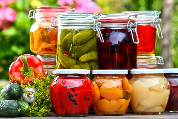 Potten van ingemaakte groenten en fruit in de tuin — Stockfoto