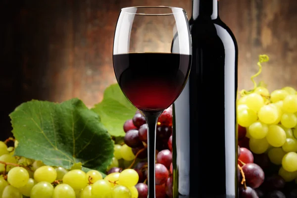 Σύνθεση με γυαλί, μπουκάλι κόκκινο κρασί και φρέσκα σταφύλια — Φωτογραφία Αρχείου