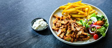 Patates kızartması, sebze ve tzatziki ile servis edilen kebap.