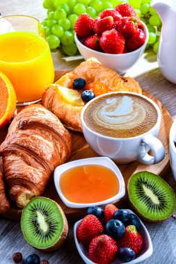 Kahve, portakal suyu, kruvasan, tahıl ve meyve ile kahvaltı. Dengeli beslenme.