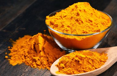 Ahşap masa üzerinde zerdeçal tozu kase ile kompozisyon.