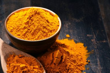 Ahşap masa üzerinde zerdeçal tozu kase ile kompozisyon.