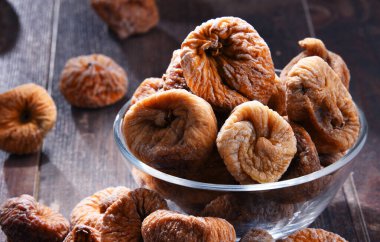 Ahşap masada bir kase kurutulmuş incir ile kompozisyon.