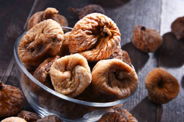 Ahşap masada bir kase kurutulmuş incir ile kompozisyon.