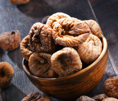 Ahşap masada bir kase kurutulmuş incir ile kompozisyon.