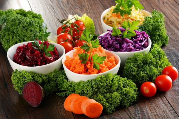 Composition with four vegetable salad bowls on wooden table — Stock Photo, Image