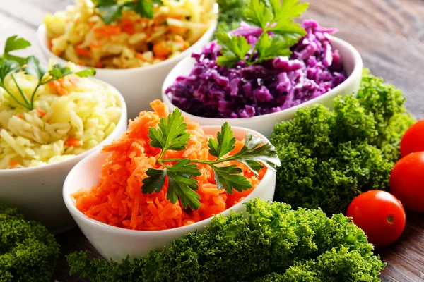 Composition with four vegetable salad bowls on wooden table — Stock Photo, Image