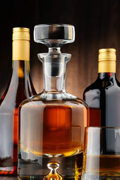 Flessen van diverse alcoholhoudende dranken en glas whisky — Stockfoto