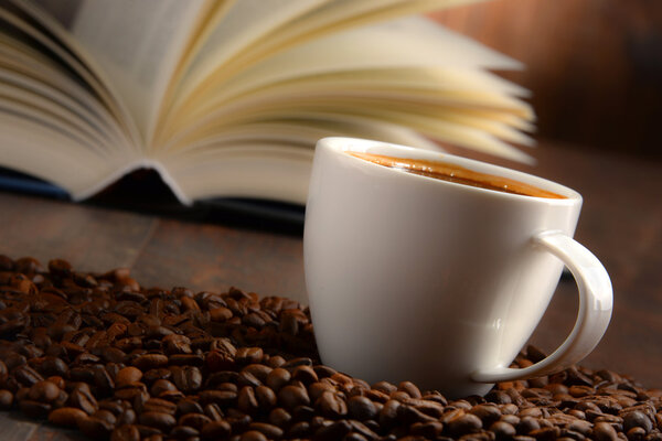 Композиция с белой чашкой кофе и открытой книгой
