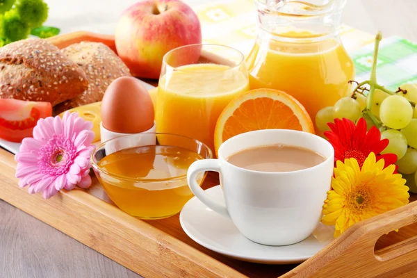 Desayuno en bandeja servido con café, jugo, huevo y panecillos — Foto de Stock