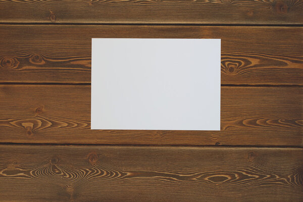 Blank white paper on a dark wooden table. Top view. Toned