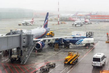 Rusya, Moskova, Sheremetyevo havaalanı, 01.04.2021. Uçak iniş terminalinin yanında duruyor, çalışanlar uçuştan önce kontrol için hazırlanıyorlar. Uçuş ertelendi. Pencerenin yanında bekletiliyor.