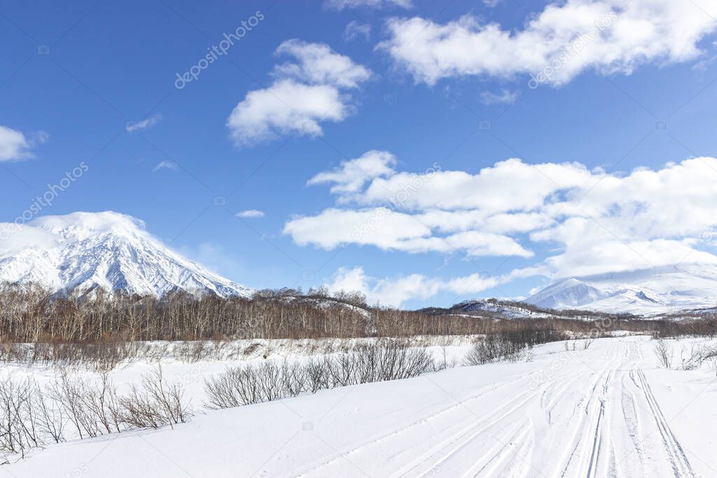 Russia, Kamchatka Volcanoes Natural Park. A snow-covered road along a frozen riverbed in the direction of an icy volcano. Winter hiking to the Avachinsky pass. August 20 is the day of the volcano in Kamchatka