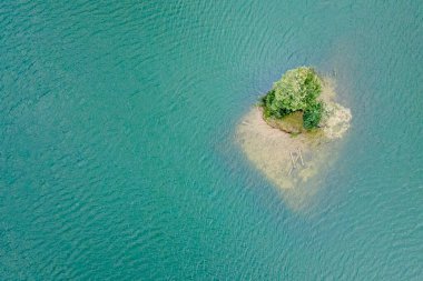 Okyanusun ortasında ağaç olan küçük bir ada, havadan çekilmiş bir fotoğraf. Sıcak turkuaz su ve martılar. 2022 yılının yeni yıl konsepti ve kendini izole etme..