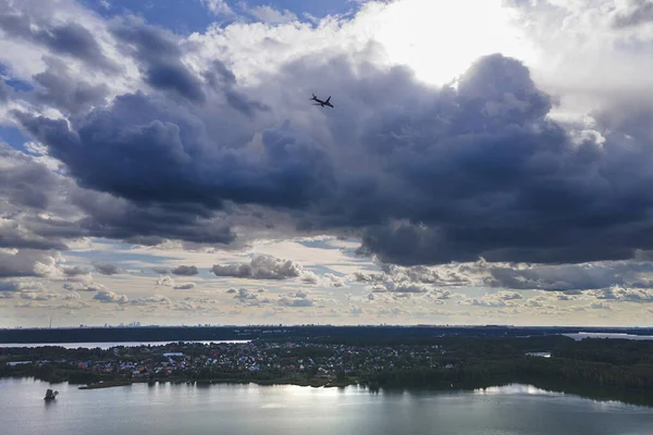 Samolot Przelatuje Nad Jeziorem Miastem Wysoko Chmurach Których Świeci Słońce — Darmowe zdjęcie stockowe