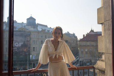 Genç bir kadın, eski kasabaya bakan evinin balkonunda dinleniyor..